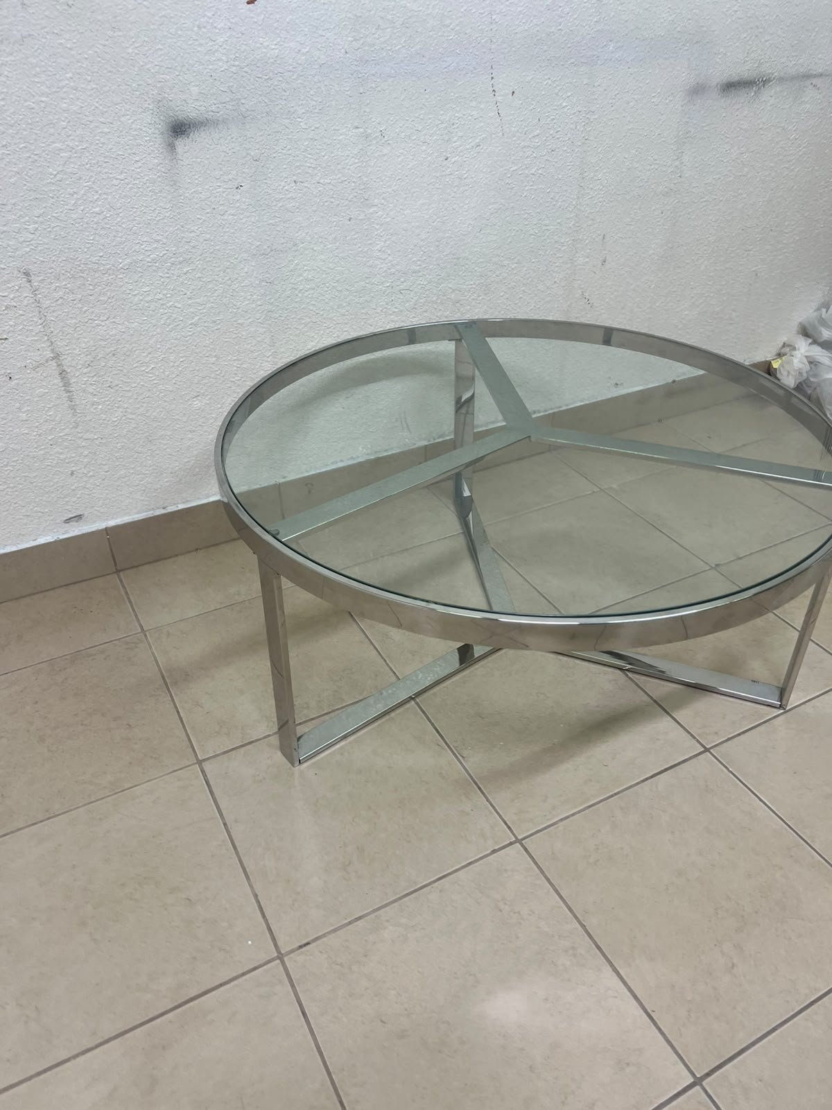 A round coffee table featuring a silver-colored metal frame (steel or chrome), a clear glass top, and a geometric crisscross base design. - Image 4