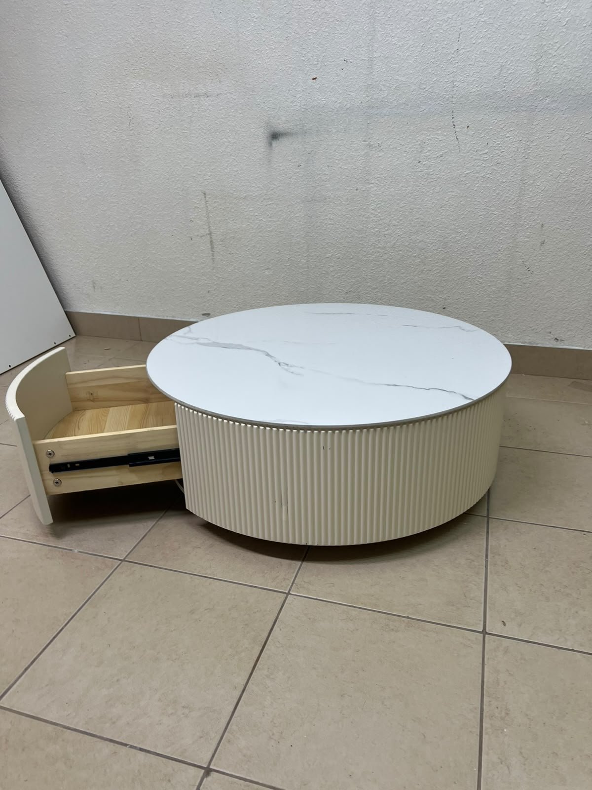 This round coffee table is elegant, featuring a cream-colored ribbed base and a stone tabletop with a marble-like pattern. - Image 3