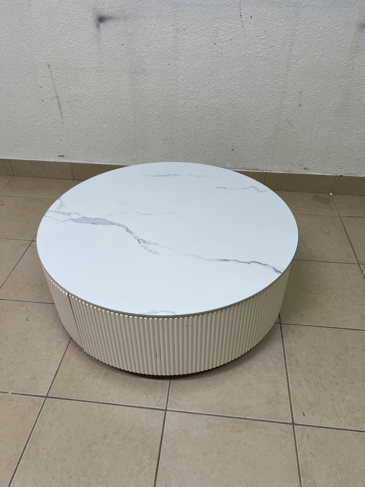 This round coffee table is elegant, featuring a cream-colored ribbed base and a stone tabletop with a marble-like pattern. - Image 11