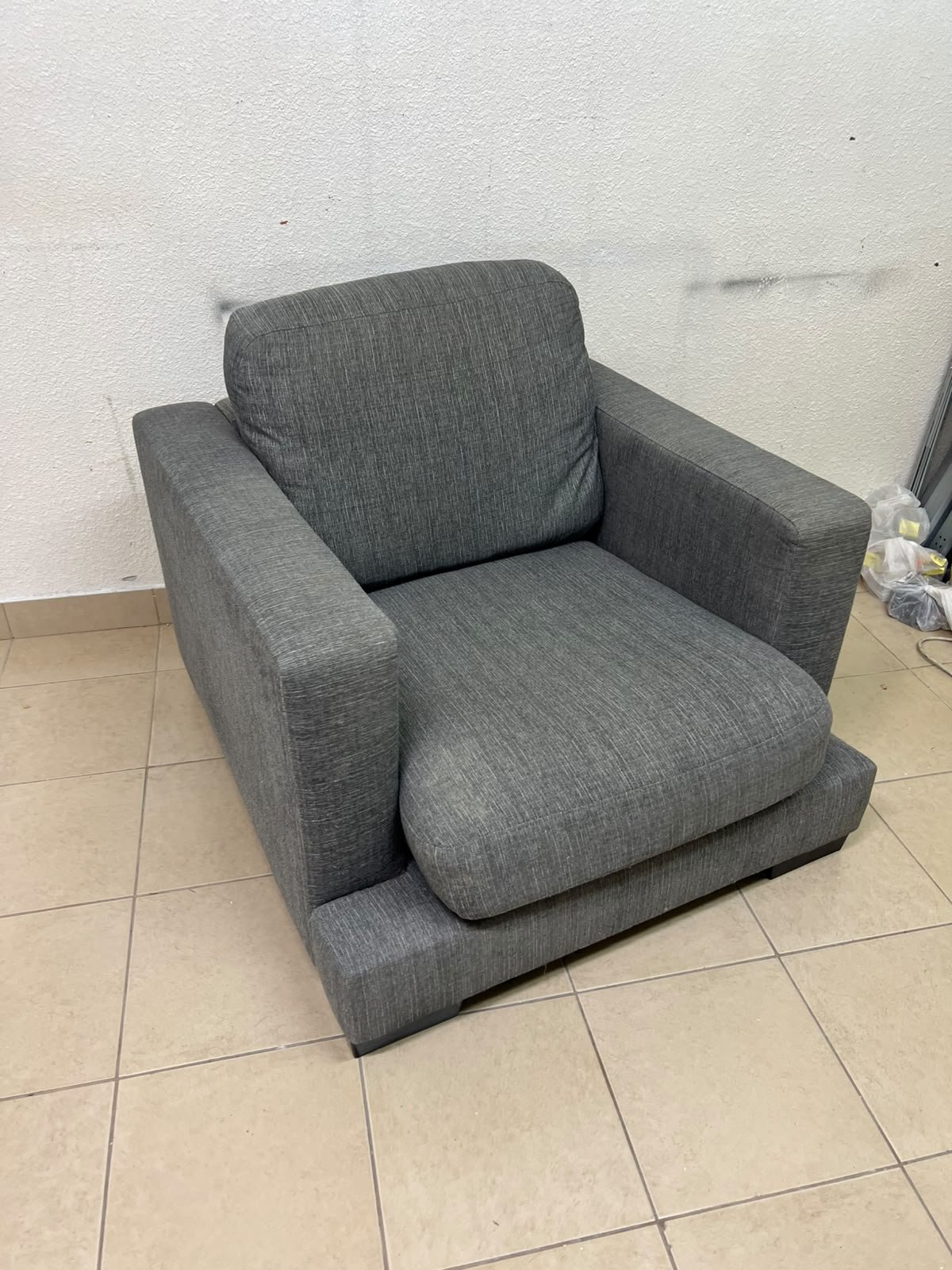 This is a single-seater chair (armchair) featuring a modern design, upholstered in gray fabric, with wide, square armrests.