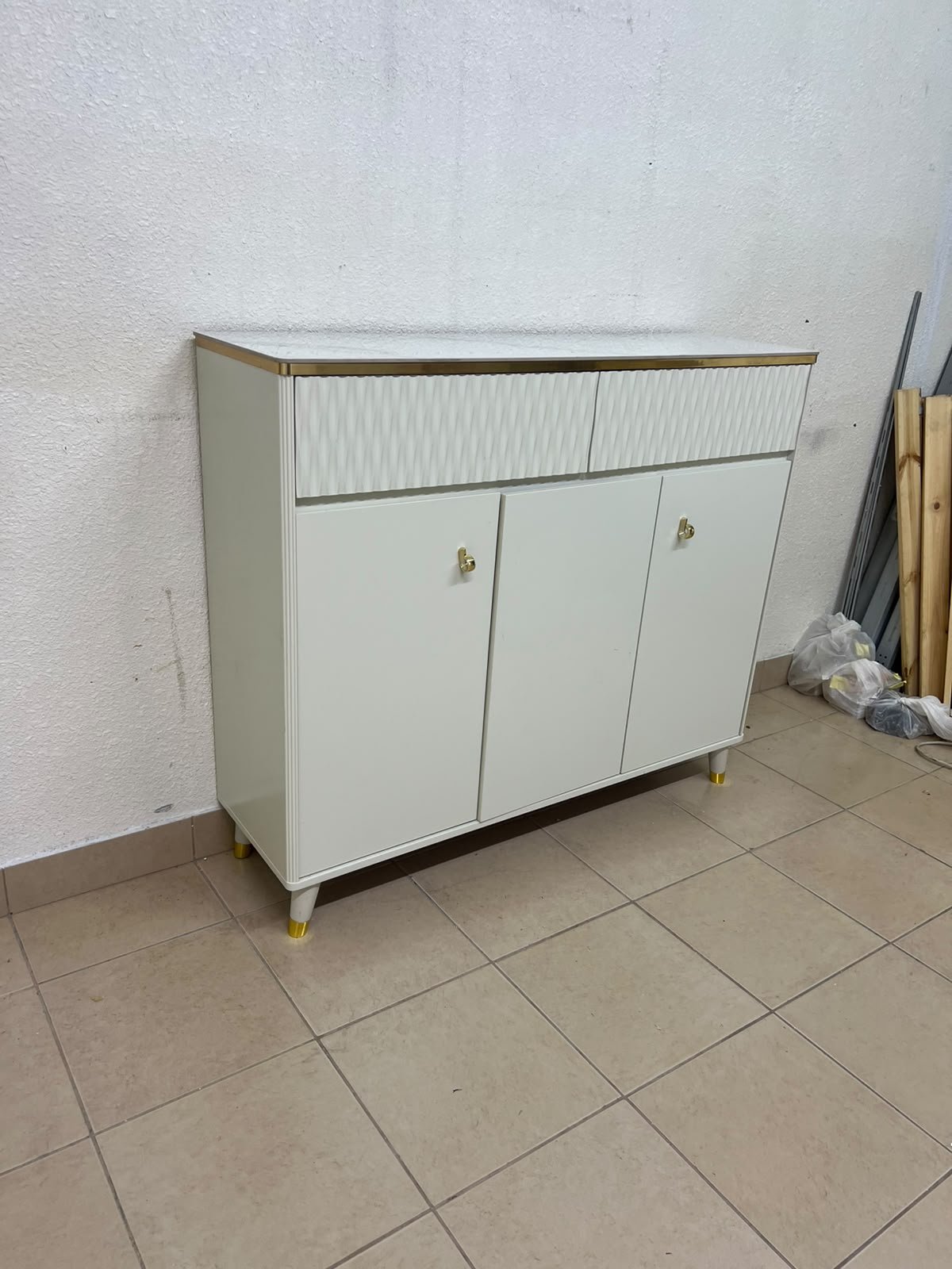 A white shoe cabinet or entryway storage unit (console) featuring a modern design, ribbed upper drawers, and gold accents on the handles and legs. - Image 2