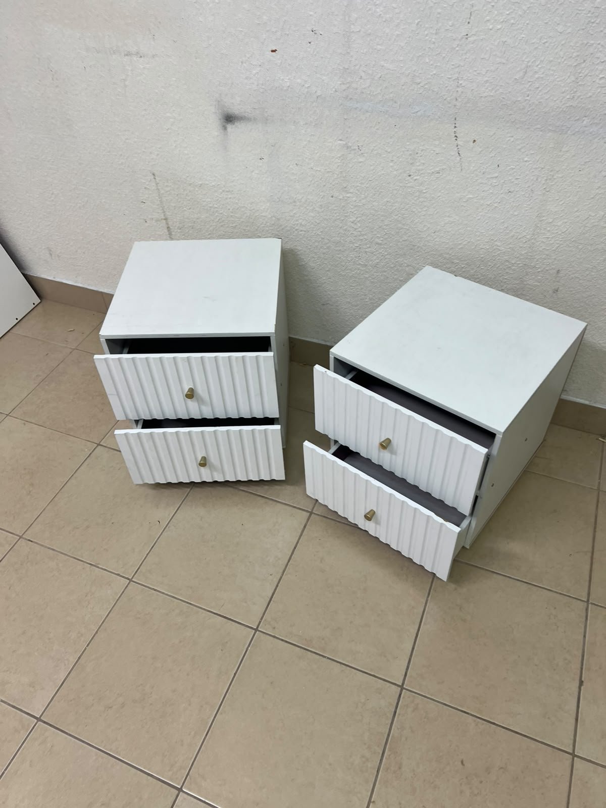 Modern white bedside tables featuring an elegant vertical ribbed design, with attractive gold accents on the handles and base. - Image 2