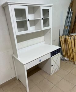 A white study desk featuring an overhead storage unit (a hutch or bookcase with glass-fronted cabinets), shelves, and a spacious work surface, along with a drawer and a lower cabinet accented with blue and gold star motifs and geometric patterns; a practical design suitable for children's or students' rooms for organizing books and school supplies. - Image 2