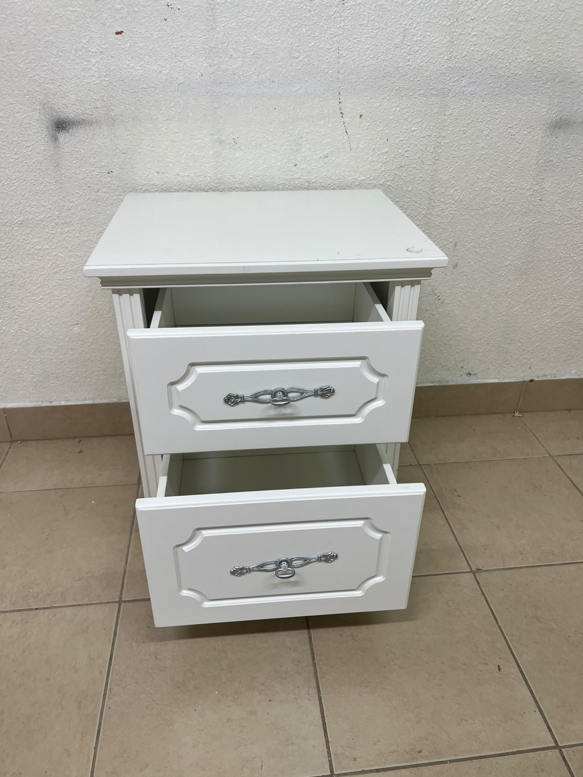 The elegant white side table with two drawers is distinguished by its decorative details and prominent silver handles. - Image 8