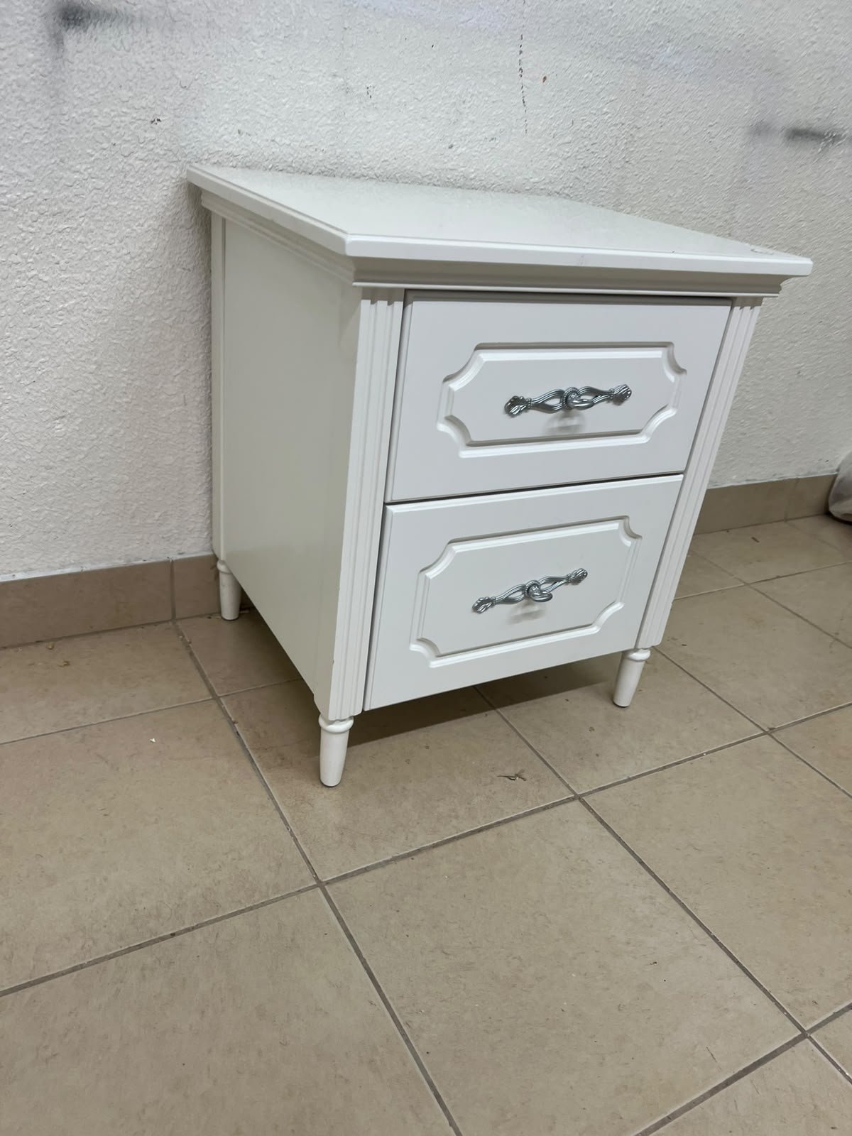 The elegant white side table with two drawers is distinguished by its decorative details and prominent silver handles. - Image 9