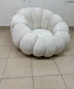 The Fana "Flower" chair from Home Centre is a lounge chair featuring a floral-inspired design and upholstered in soft, comfortable bouclé fabric; it is distinguished by its rounded shape—resembling petals or a pumpkin.