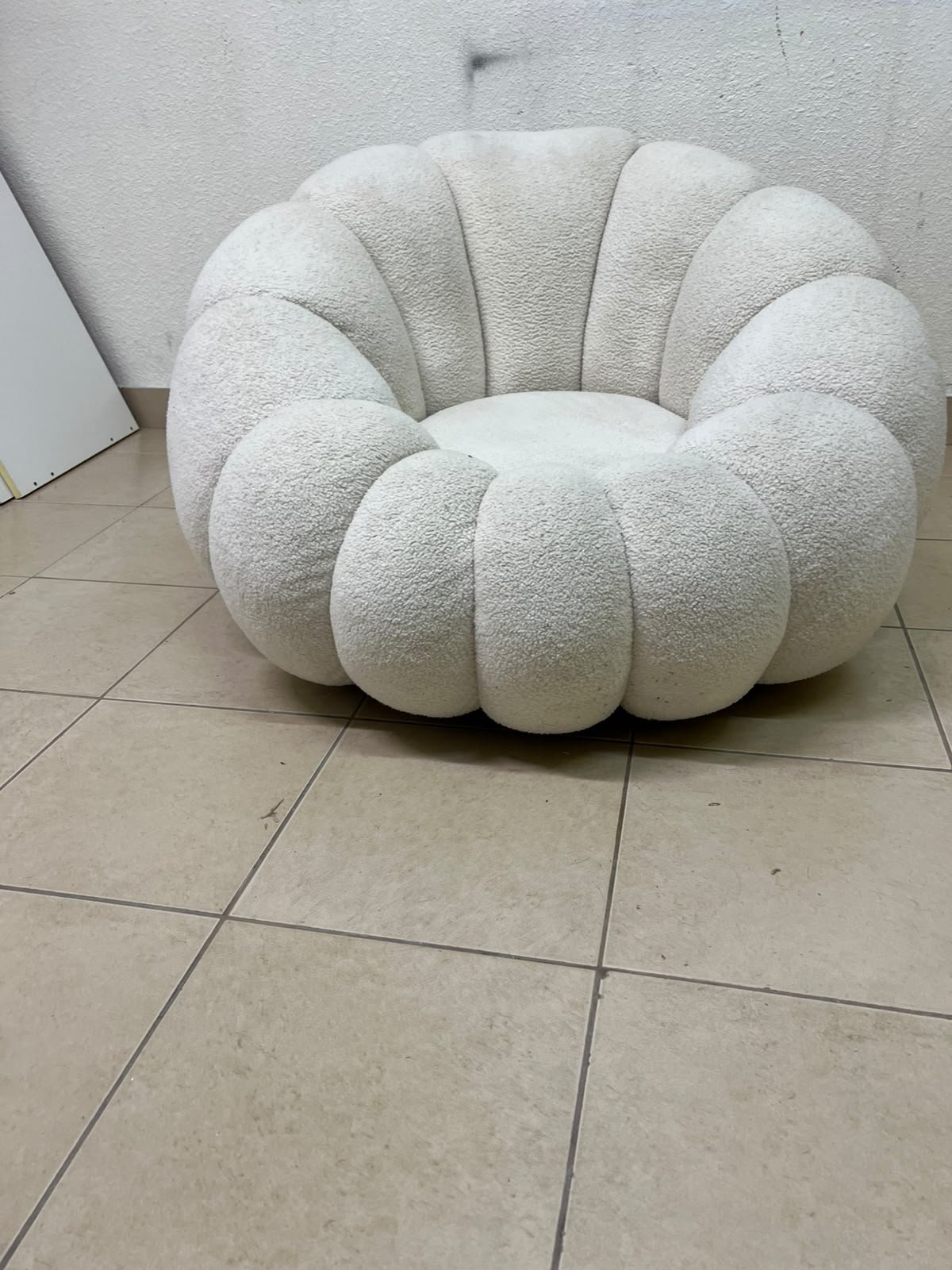The Fana "Flower" chair from Home Centre is a lounge chair featuring a floral-inspired design and upholstered in soft, comfortable bouclé fabric; it is distinguished by its rounded shape—resembling petals or a pumpkin. - Image 3