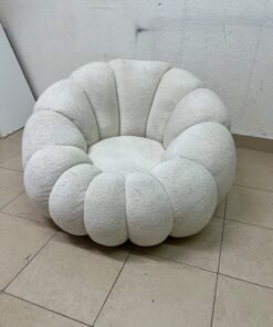 The Fana "Flower" chair from Home Centre is a lounge chair featuring a floral-inspired design and upholstered in soft, comfortable bouclé fabric; it is distinguished by its rounded shape—resembling petals or a pumpkin. - Image 6