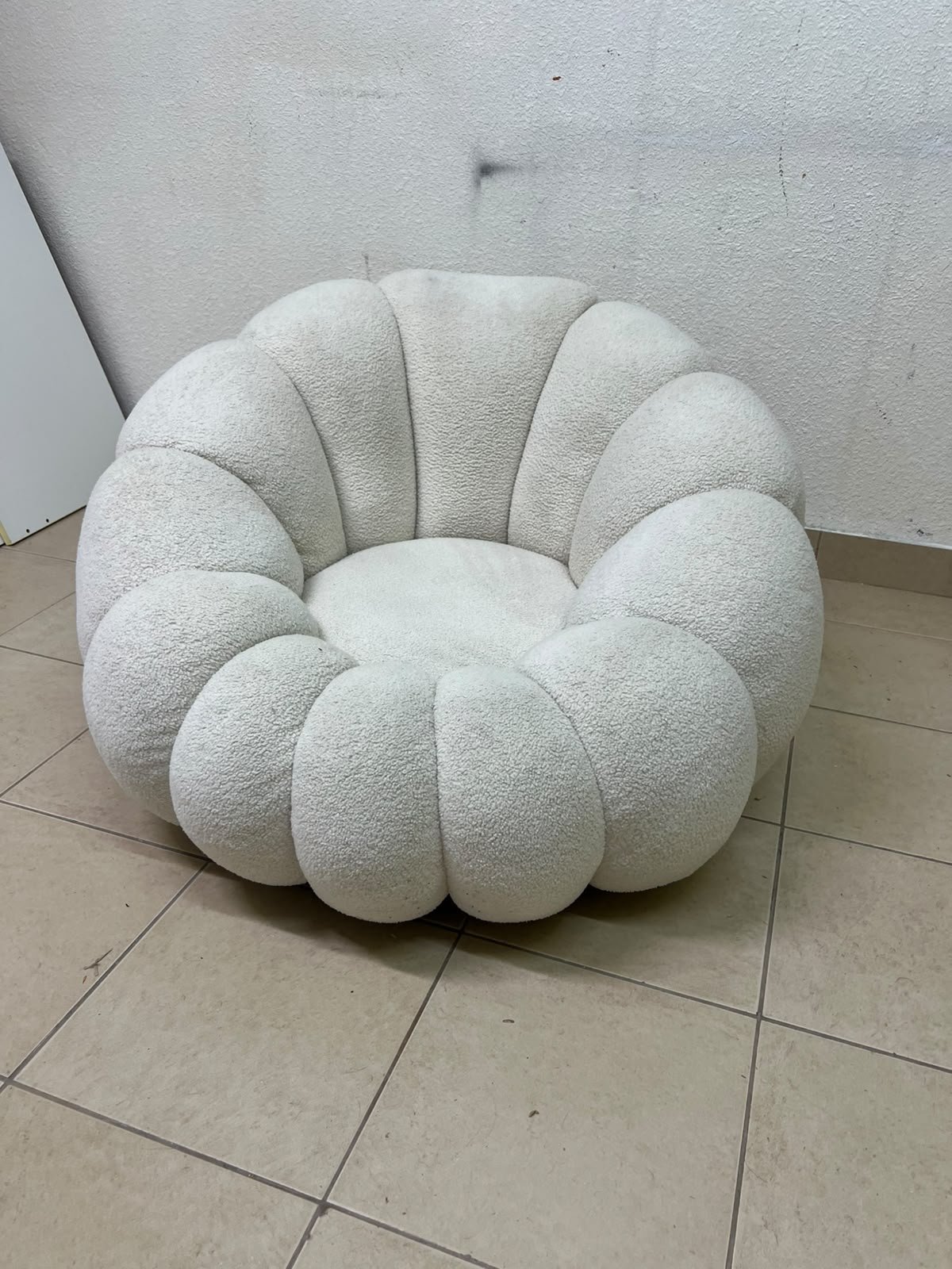The Fana "Flower" chair from Home Centre is a lounge chair featuring a floral-inspired design and upholstered in soft, comfortable bouclé fabric; it is distinguished by its rounded shape—resembling petals or a pumpkin. - Image 6