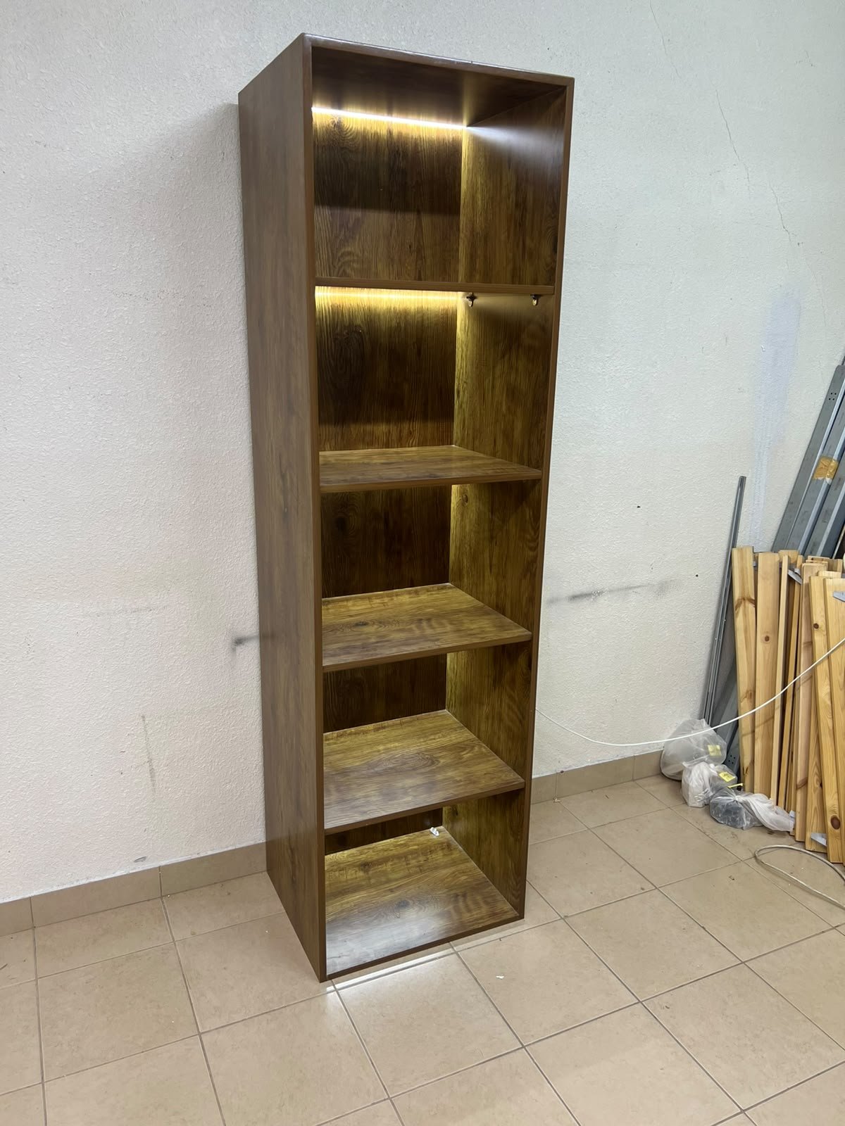 A vertical, 5-shelf wooden storage organizer featuring an open-back cube design and built-in LED lighting that adds a warm, modern touch to the upper shelves.