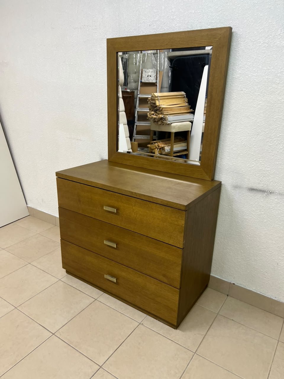 A wooden drawer unit (dressing table) featuring three drawers and metal handles, accompanied by a square mirror with a matching wooden frame—resembling designs found at brands like Pan Emirates or Home Centre.