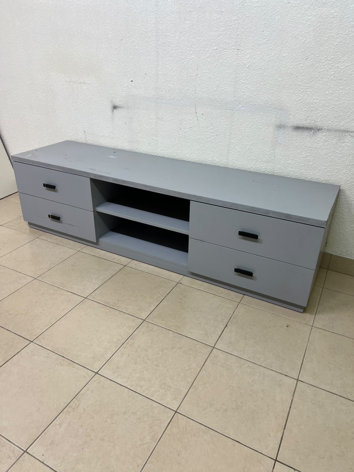 A grey TV stand featuring a modern design and side drawers equipped with stylish black handles.