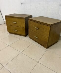 Two wooden side tables in a warm brown hue, featuring an elegant design with two drawers and distinctive metal handles.