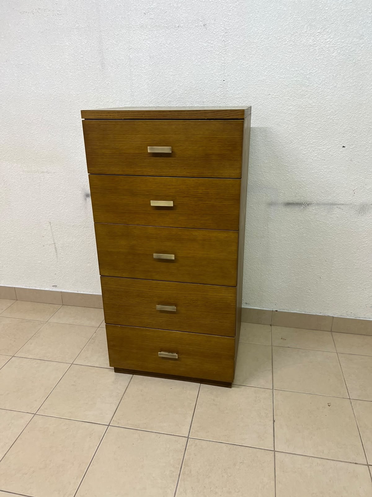 A tall, classic-style wooden chest of drawers, featuring elegant gold metal handles neatly arranged on each drawer.