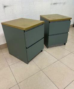 A bedside table featuring a minimalist design, grey-green drawers, and a wooden or yellowish top surface; the style resembles modern storage furniture.