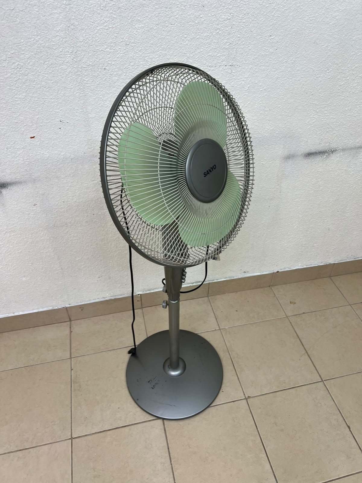 A Sanyo-branded grey pedestal fan featuring light green blades and a circular base. - Image 8