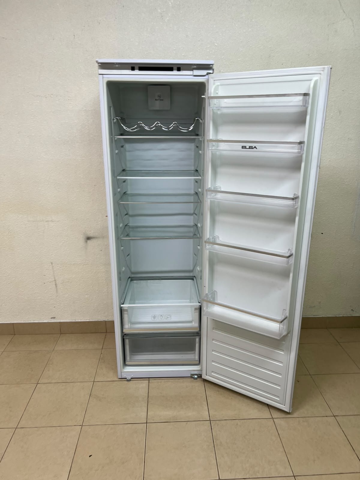 An Elba built-in single-door refrigerator featuring a white design, adjustable glass shelves, and a metal bottle rack.