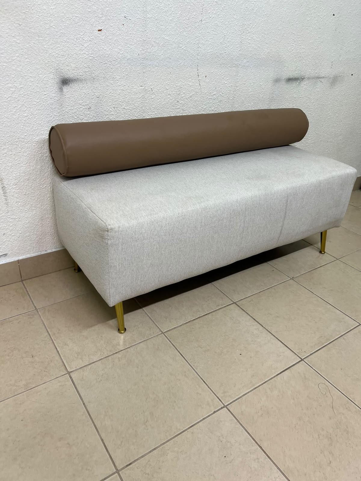 The light-gray upholstered seat, featuring a brown cylindrical backrest and gold legs, is a stylish, modern piece of furniture that adds a distinctive touch to the décor. - Image 2