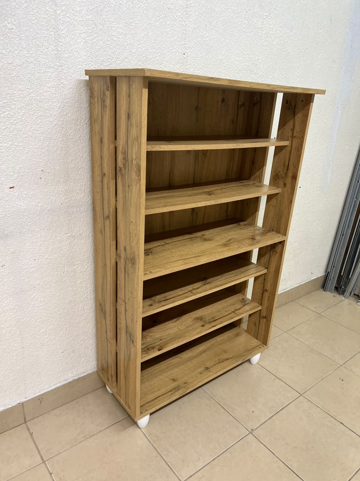 The wooden shoe cabinet, featuring open shelves and small white legs, is a practical and stylish piece for organizing the entryway. - Image 4