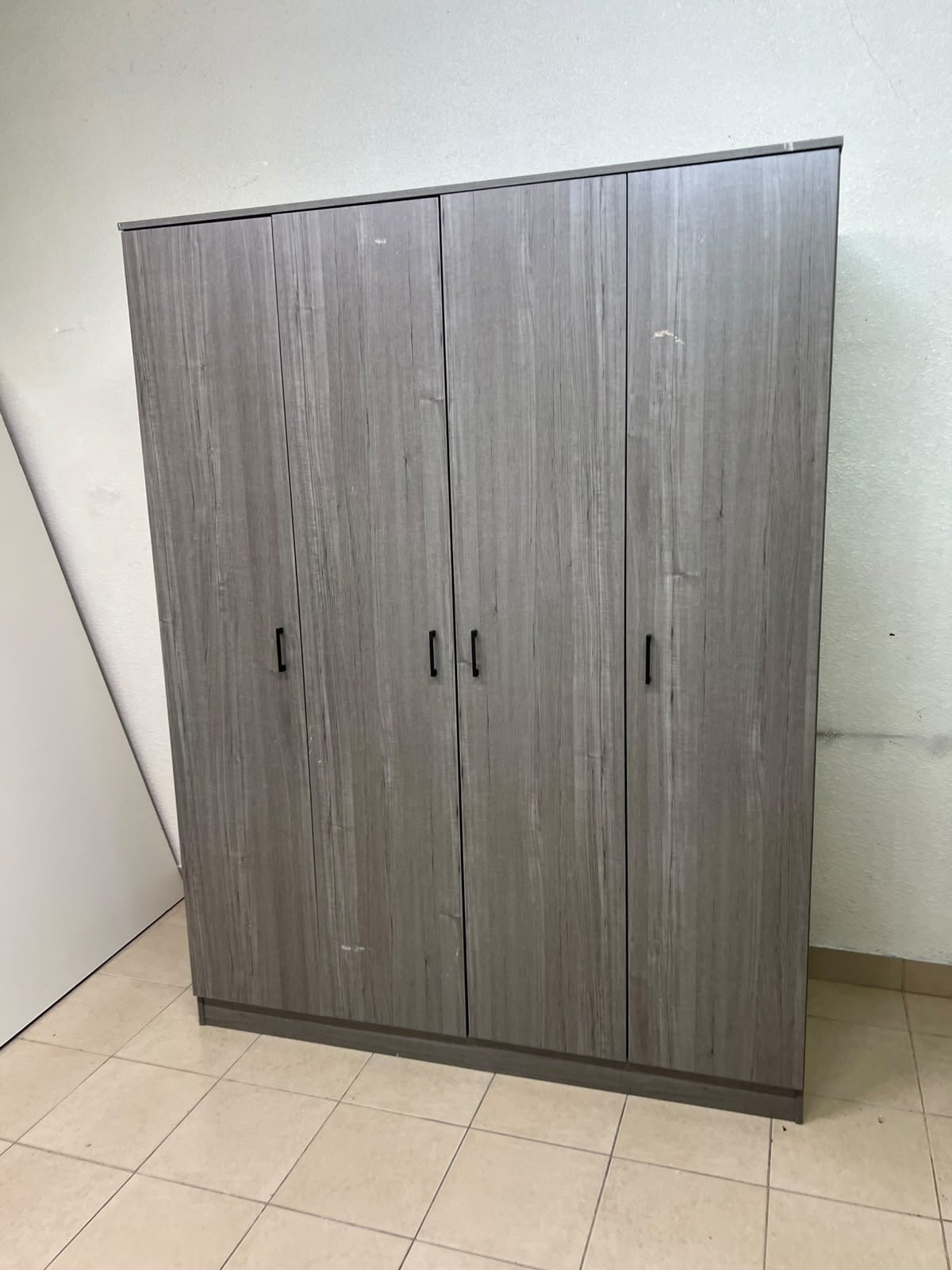 The image shows the Jamora four-door wardrobe from Danube Home, featuring a warm grey color and a practical design with hinged doors and simple black handles. - Image 3