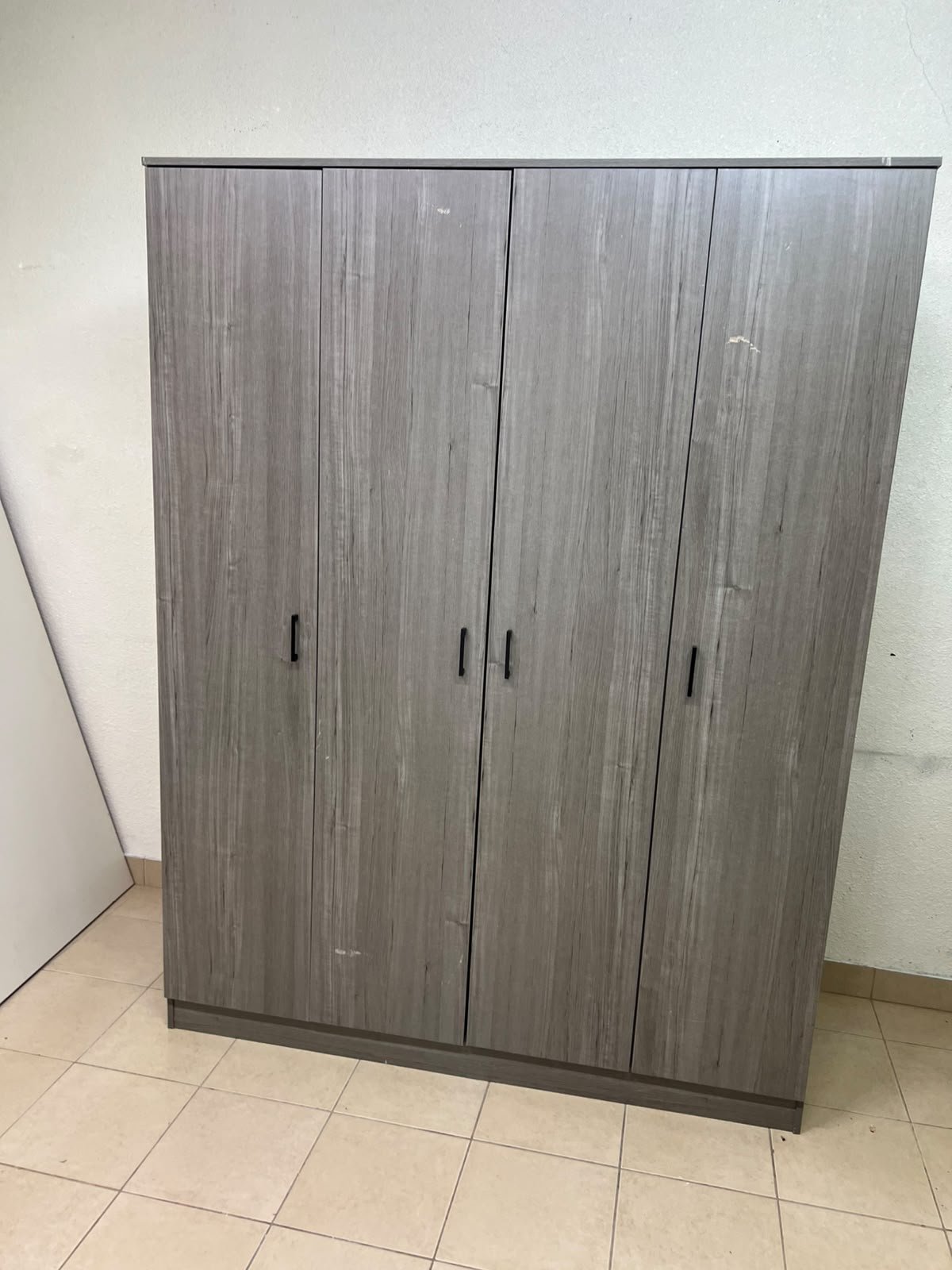 The image shows the Jamora four-door wardrobe from Danube Home, featuring a warm grey color and a practical design with hinged doors and simple black handles. - Image 7