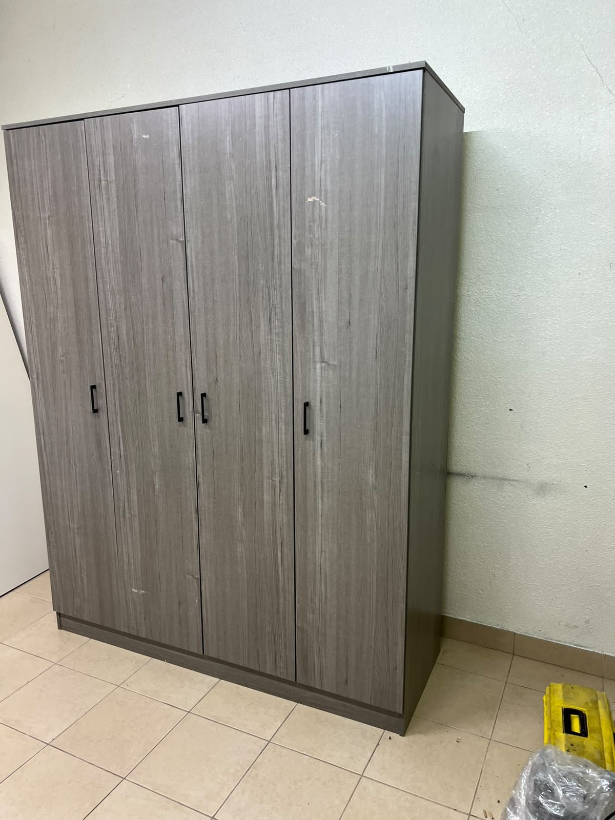The image shows the Jamora four-door wardrobe from Danube Home, featuring a warm grey color and a practical design with hinged doors and simple black handles. - Image 8