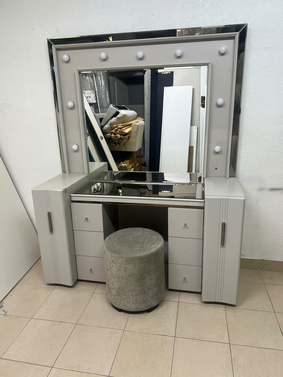 A beige Home Centre vanity table featuring a modern design, ambient mirror lighting, and an elegant round velvet stool.