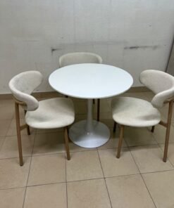 A white round dining table set featuring upholstered chairs with curved backrests and wooden legs; its design resembles the IKEA DOCKSTA / KRYLBO set.