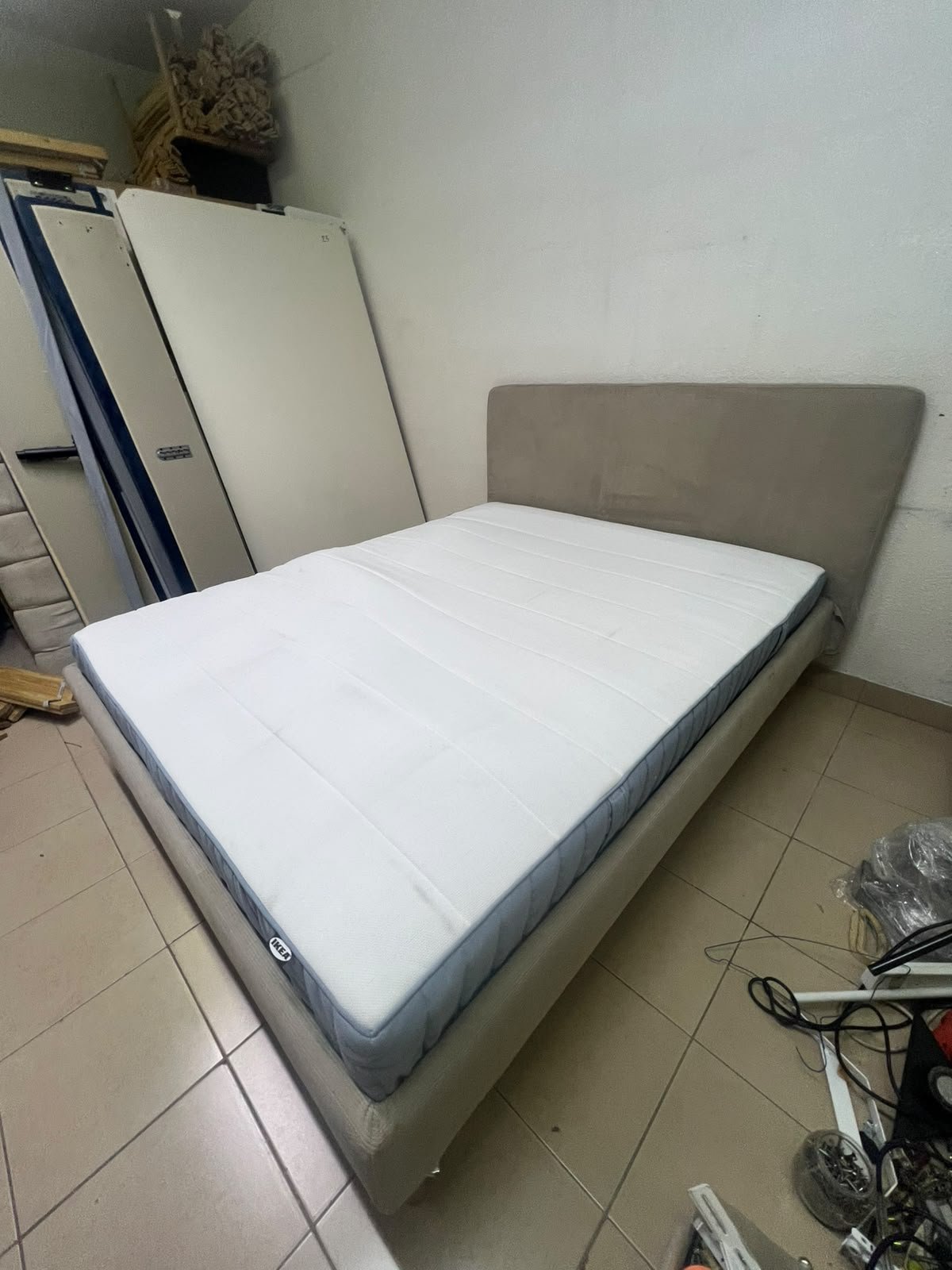 An IKEA bed with a foam and spring mattress—resembling the VALEVÅG or VESTERÖY models—featuring an upholstered bed frame in light gray or beige. - Image 2