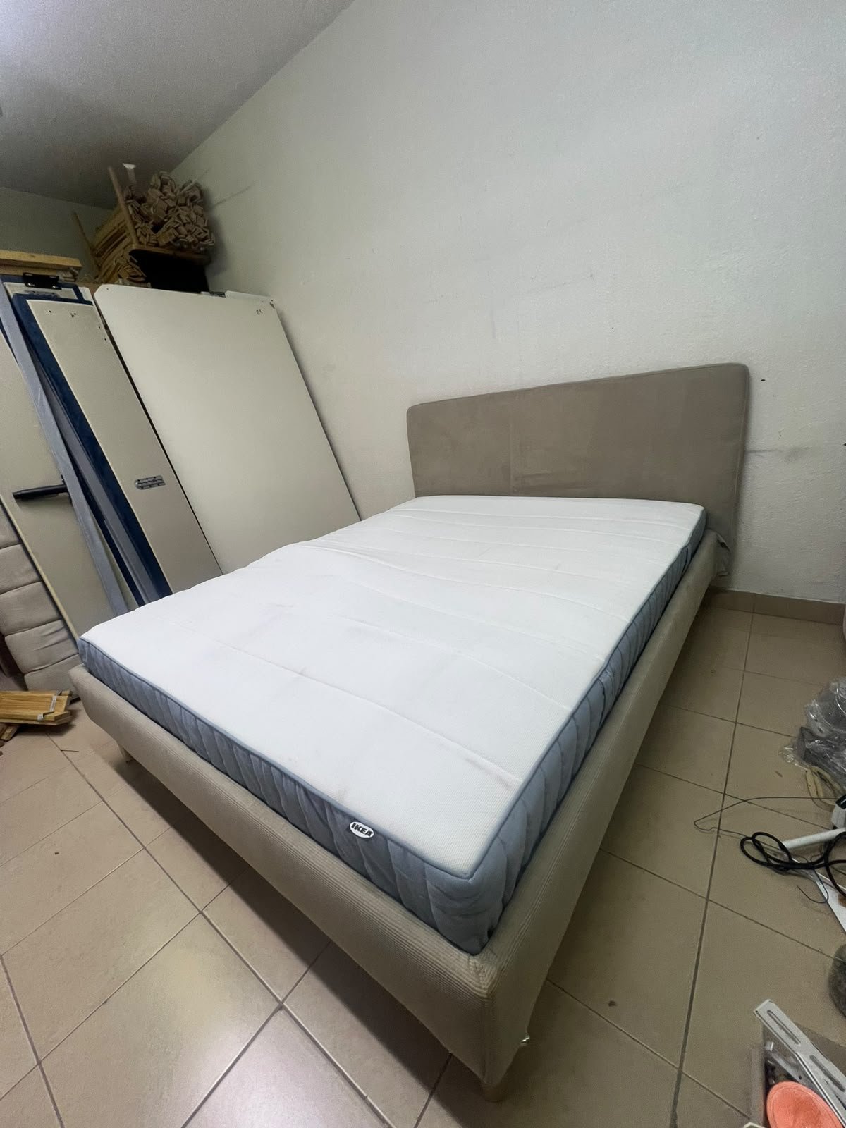 An IKEA bed with a foam and spring mattress—resembling the VALEVÅG or VESTERÖY models—featuring an upholstered bed frame in light gray or beige. - Image 4