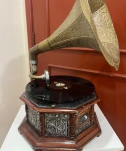 A vintage-style gramophone featuring an octagonal wooden base adorned with hand-engraved metalwork and a large, ornate brass horn, bearing the famous "His Master's Voice" logo.