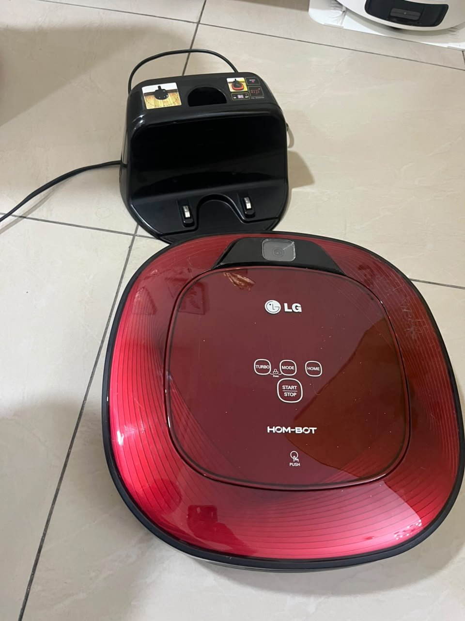 Red square-shaped robotic vacuum cleaner by LG (model LG Hom-Bot VR6270LVMB) with its charging base.