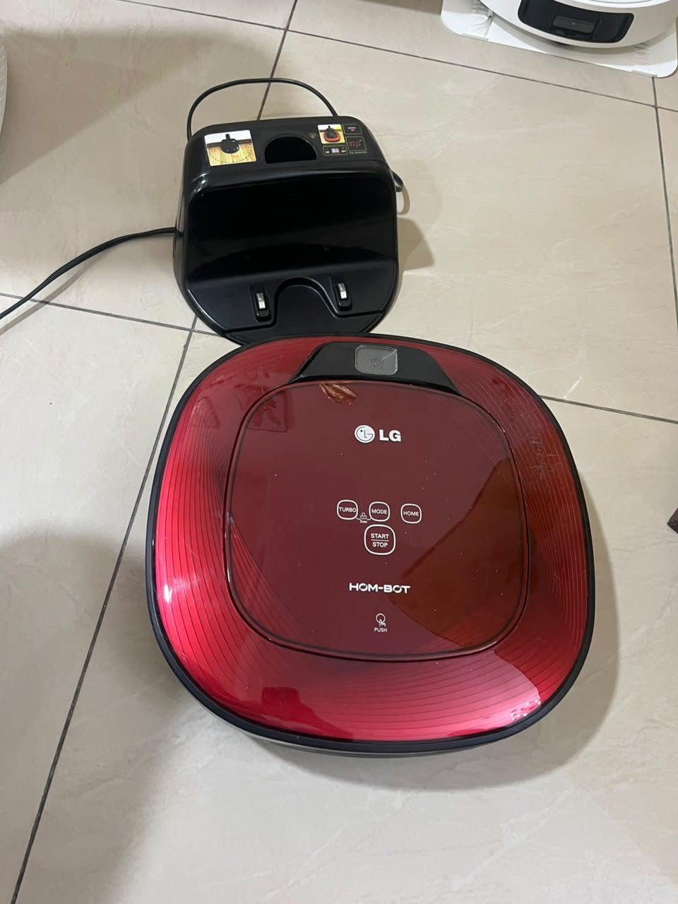 Red square-shaped robotic vacuum cleaner by LG (model LG Hom-Bot VR6270LVMB) with its charging base. - Image 4
