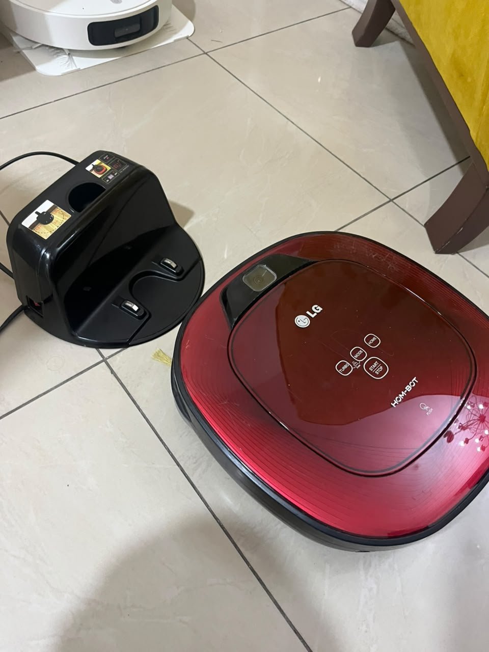 Red square-shaped robotic vacuum cleaner by LG (model LG Hom-Bot VR6270LVMB) with its charging base. - Image 5