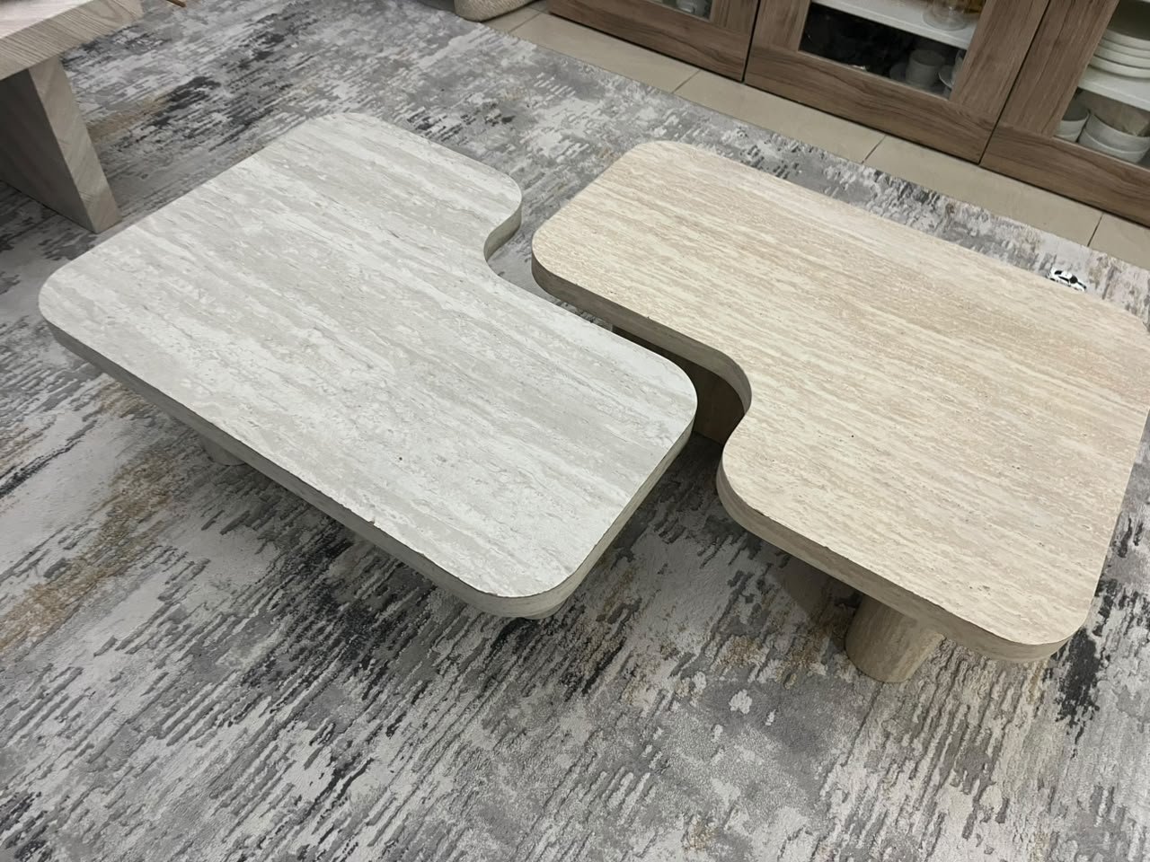 A modern two-piece coffee table set featuring an interlocking geometric design in beige, with a pattern that mimics stone or travertine.