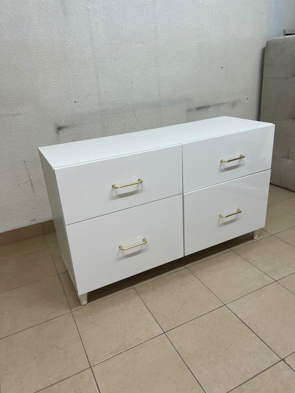 A modern, low-profile white chest of drawers (dresser) featuring a soft white finish, four spacious drawers (or double-fronted drawers), and gold or copper-toned pulls, all set on raised white legs. The design resembles contemporary storage units like the IKEA BESTÅ system or similar four-drawer cabinets. - Image 3