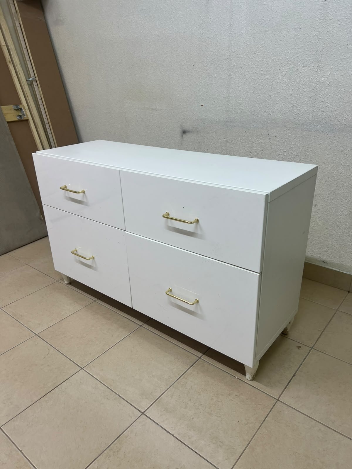 A modern, low-profile white chest of drawers (dresser) featuring a soft white finish, four spacious drawers (or double-fronted drawers), and gold or copper-toned pulls, all set on raised white legs. The design resembles contemporary storage units like the IKEA BESTÅ system or similar four-drawer cabinets. - Image 4