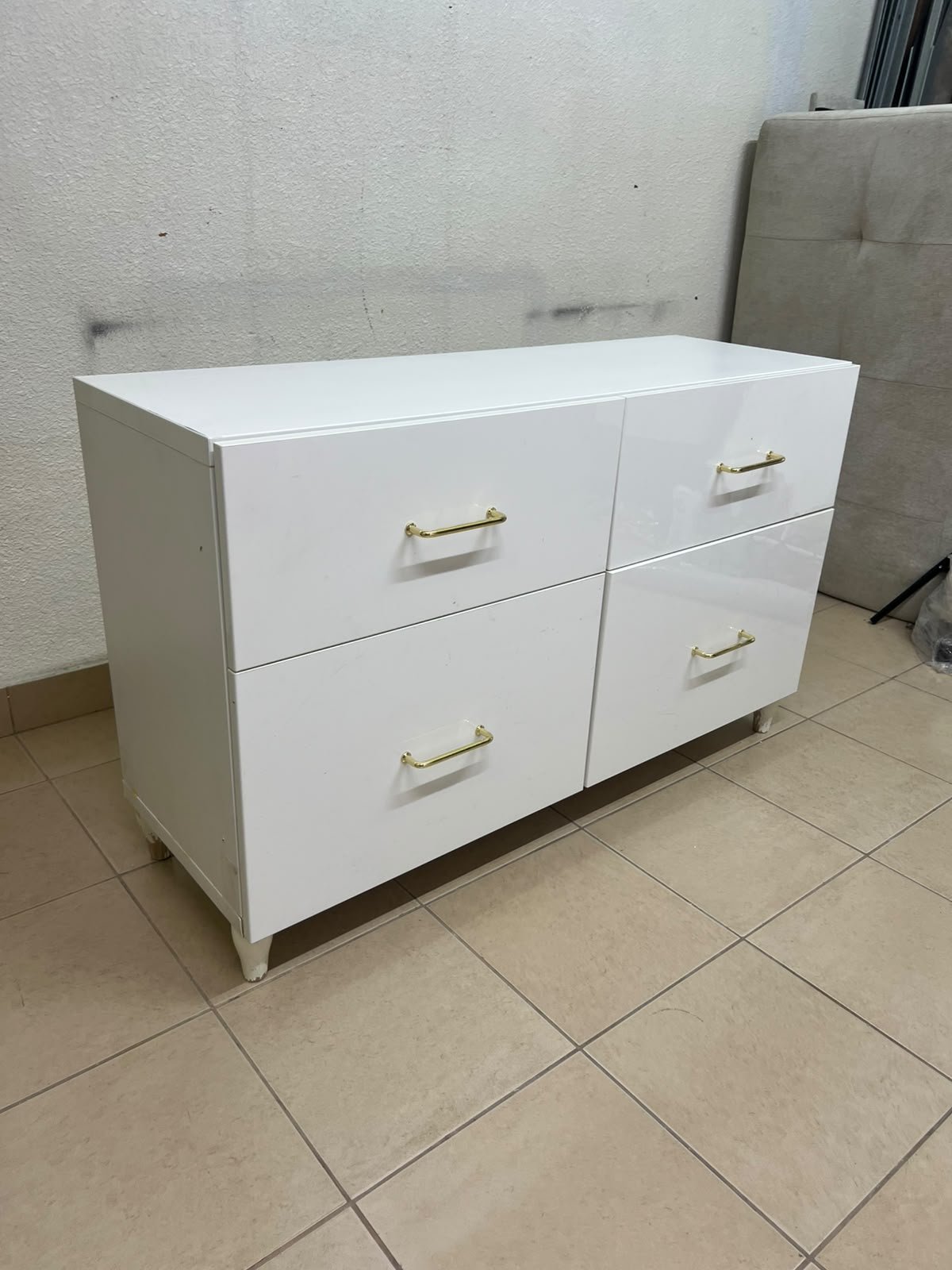 A modern, low-profile white chest of drawers (dresser) featuring a soft white finish, four spacious drawers (or double-fronted drawers), and gold or copper-toned pulls, all set on raised white legs. The design resembles contemporary storage units like the IKEA BESTÅ system or similar four-drawer cabinets. - Image 5