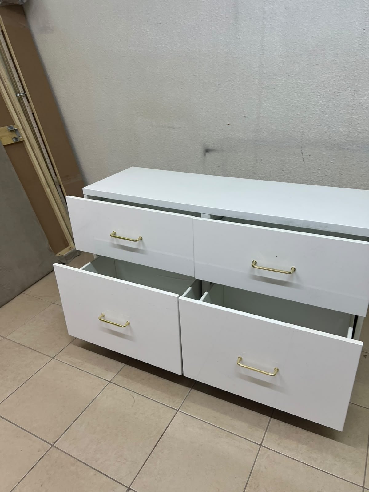 A modern, low-profile white chest of drawers (dresser) featuring a soft white finish, four spacious drawers (or double-fronted drawers), and gold or copper-toned pulls, all set on raised white legs. The design resembles contemporary storage units like the IKEA BESTÅ system or similar four-drawer cabinets. - Image 7