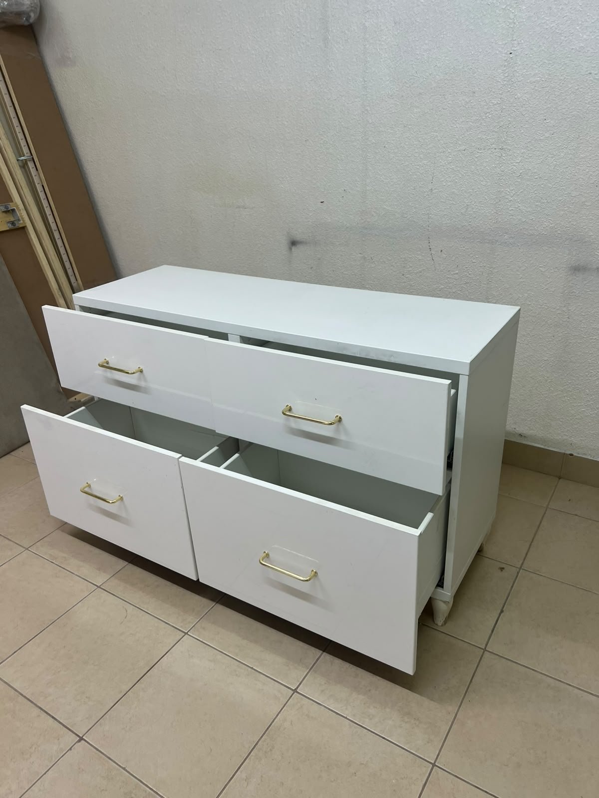 A modern, low-profile white chest of drawers (dresser) featuring a soft white finish, four spacious drawers (or double-fronted drawers), and gold or copper-toned pulls, all set on raised white legs. The design resembles contemporary storage units like the IKEA BESTÅ system or similar four-drawer cabinets. - Image 8