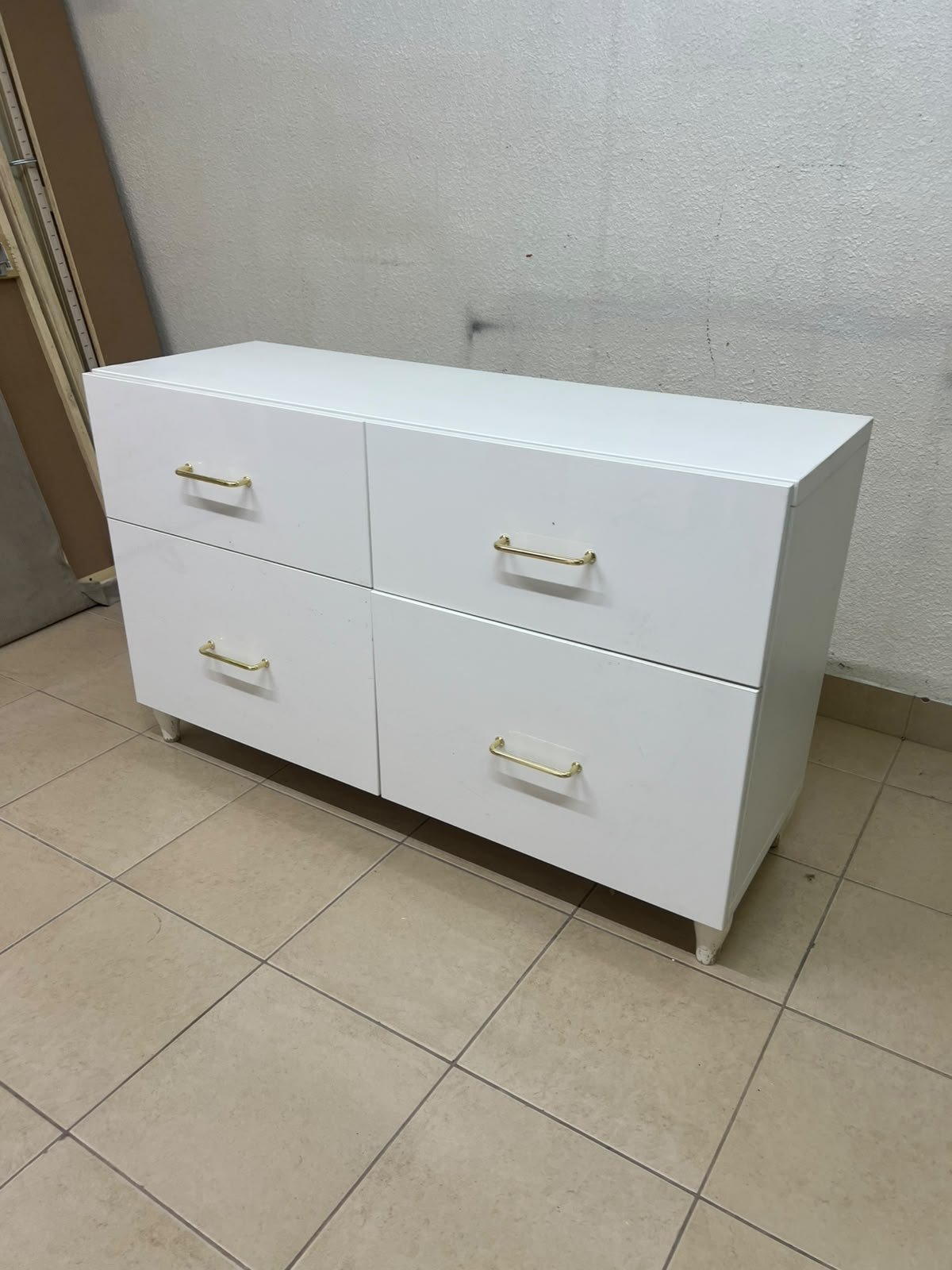 A modern, low-profile white chest of drawers (dresser) featuring a soft white finish, four spacious drawers (or double-fronted drawers), and gold or copper-toned pulls, all set on raised white legs. The design resembles contemporary storage units like the IKEA BESTÅ system or similar four-drawer cabinets. - Image 10