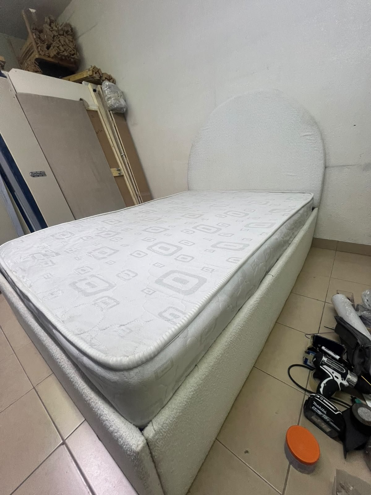A modern single bed featuring a rounded (arched) headboard, upholstered in white or light beige fabric (such as bouclé or light-colored velvet), and including a mattress. Dimensions: 140 x 200 cm.
