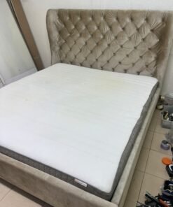 Beige upholstered double bed featuring a high, button-tufted wingback headboard. 180 x 200 cm.