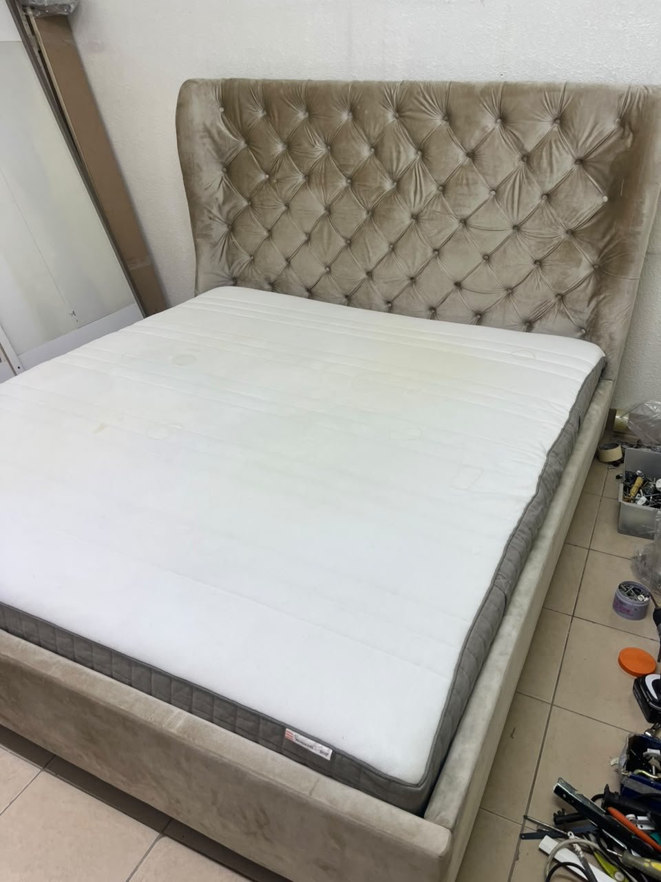 Beige upholstered double bed featuring a high, button-tufted wingback headboard. 180 x 200 cm.