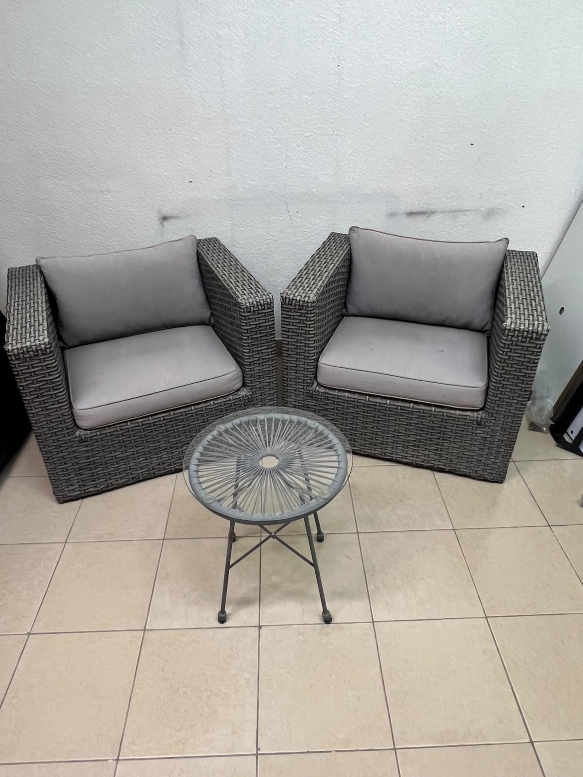 A compact outdoor seating set consisting of two grey synthetic rattan (PE Rattan) armchairs with comfortable grey cushions, plus a round table with a glass top. - Image 2