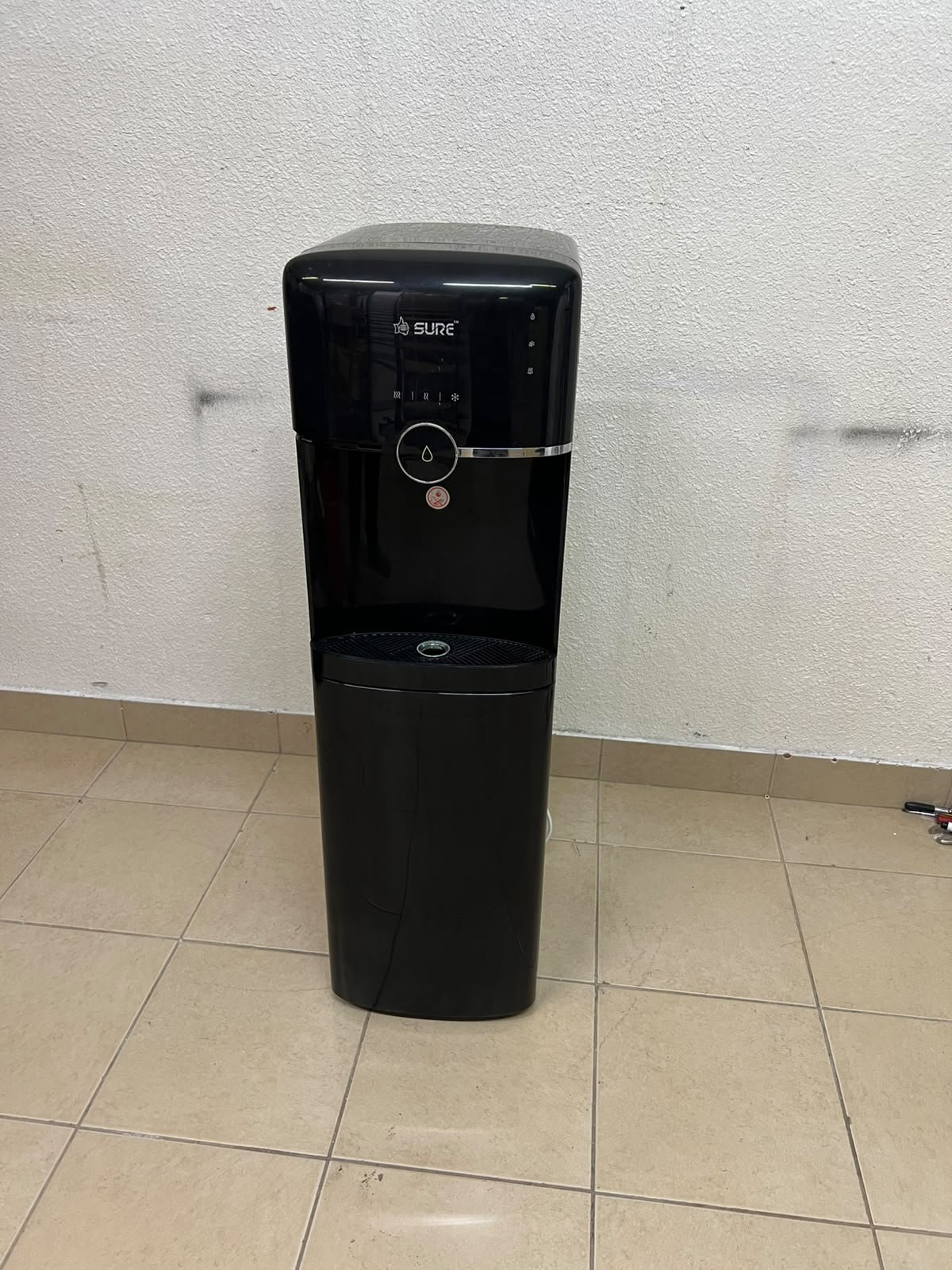A black, freestanding water cooler from Sure—specifically a bottom-loading model (such as the SBL70 or SBL1970BP)—that allows the water bottle to be easily placed inside the bottom compartment. - Image 11