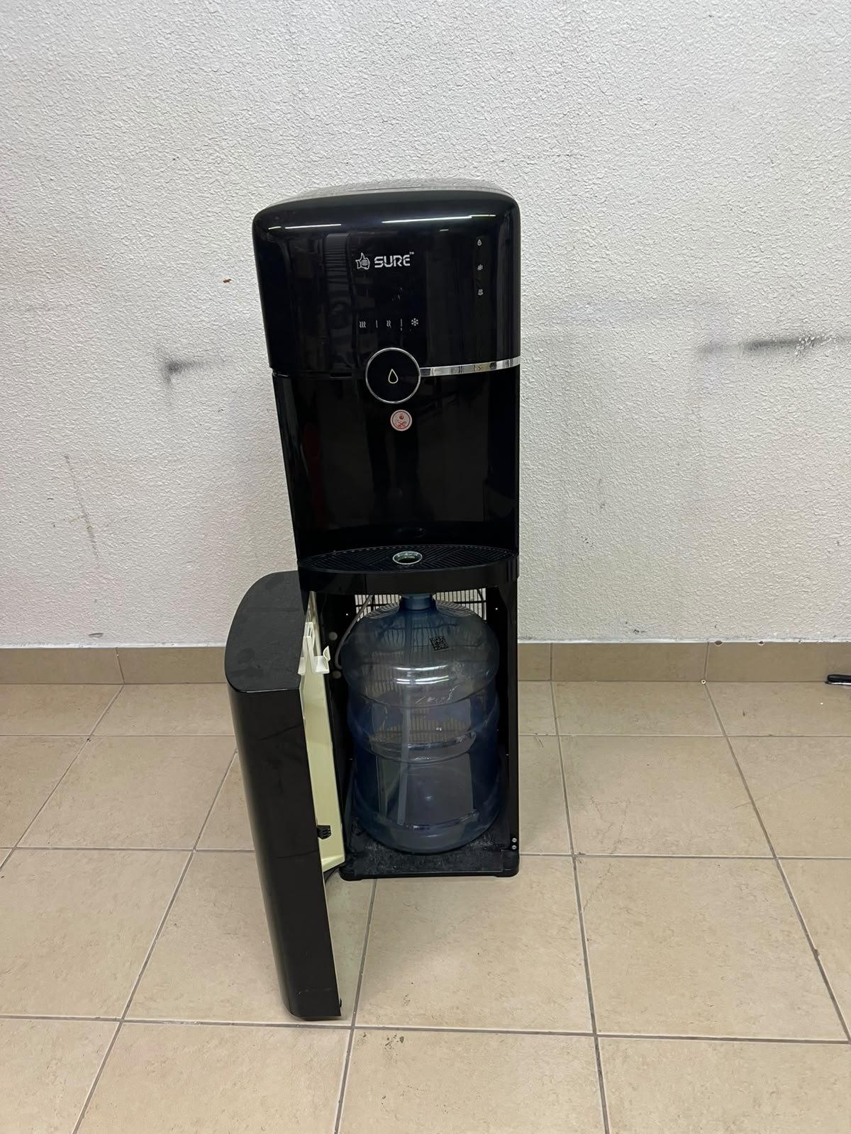 A black, freestanding water cooler from Sure—specifically a bottom-loading model (such as the SBL70 or SBL1970BP)—that allows the water bottle to be easily placed inside the bottom compartment. - Image 2