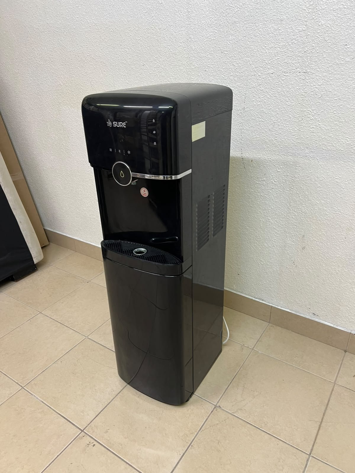 A black, freestanding water cooler from Sure—specifically a bottom-loading model (such as the SBL70 or SBL1970BP)—that allows the water bottle to be easily placed inside the bottom compartment. - Image 10