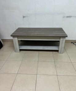 A rectangular coffee table made of engineered wood featuring a two-tone design; the tabletop comes in a greyish-brown wood finish, while the frame, legs, and lower shelf are white or light grey. It resembles the "Angelic" coffee table from Home Box.
