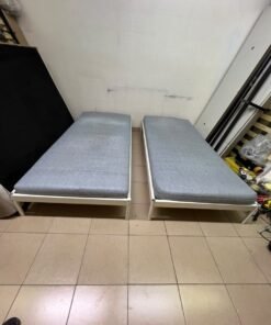 Two single beds with white metal frames, featuring lightweight foam mattresses in a light gray/blue color—similar to the ÅGOTNES foam mattress from IKEA. - Image 10